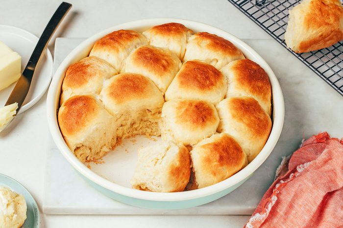 Baked potato rolls in the pan with some rolls cooling on rack, recipe for Taste of Home