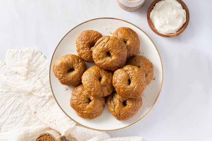 Bagels ready served on plate with side of cream cheese and tea.