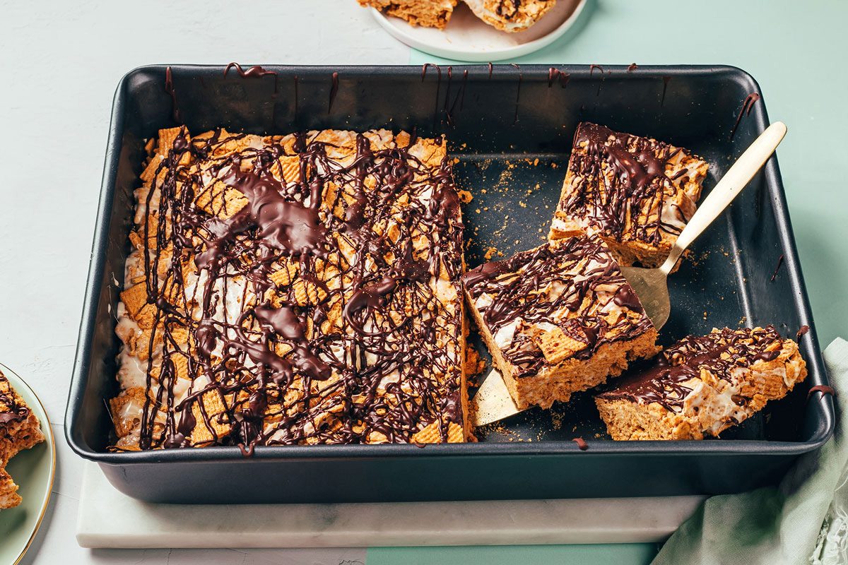 S’mores Bars chilled and cut in a baking pan, some squares showed on small plates, a recipe by Taste of Home