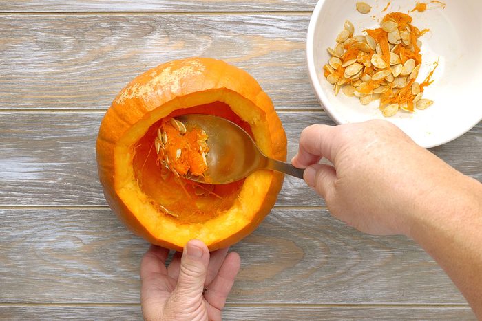 hands scooping out the insides of the pumpkin