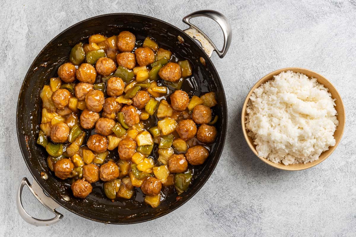 Sweet And Sour Meatballs in a pan with a side of rice