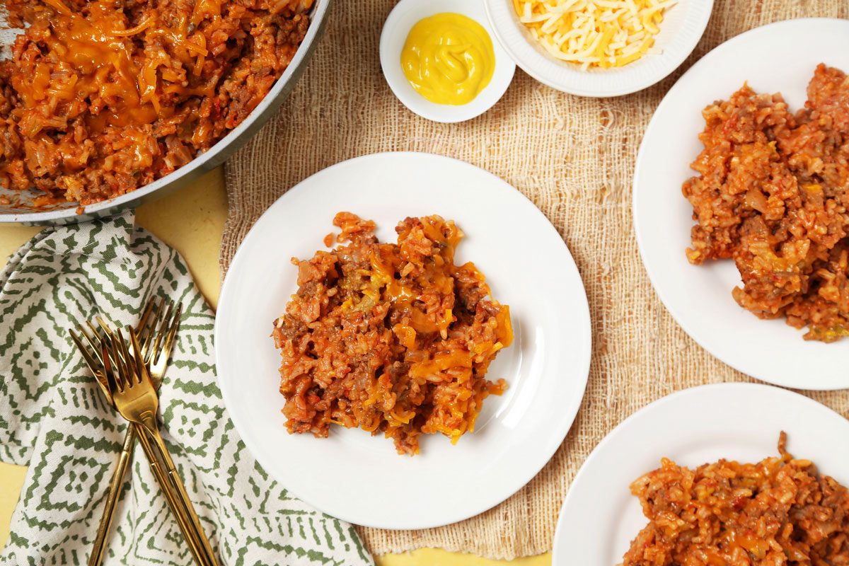Close up of Taste of Home's Hamburger Casserole served on white plates on a bright yellow surface.