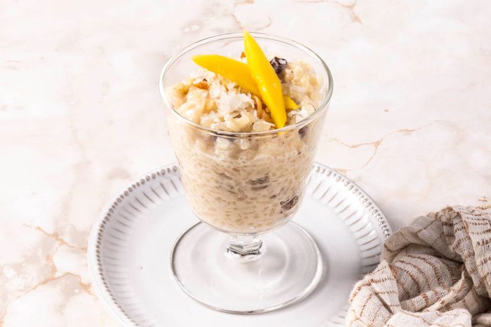 close up of Coconut Rice Pudding with mango on top 3/4 view on marble