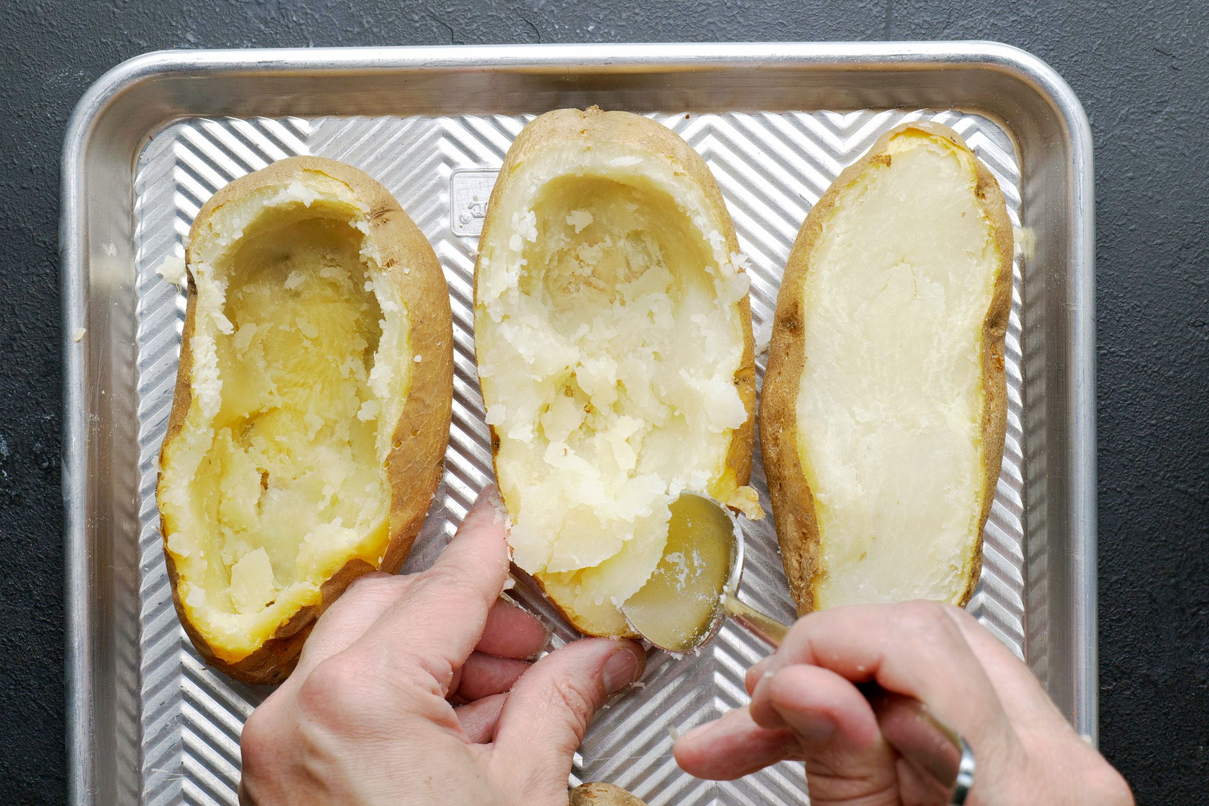 Scooping out potato pulp with a spoon