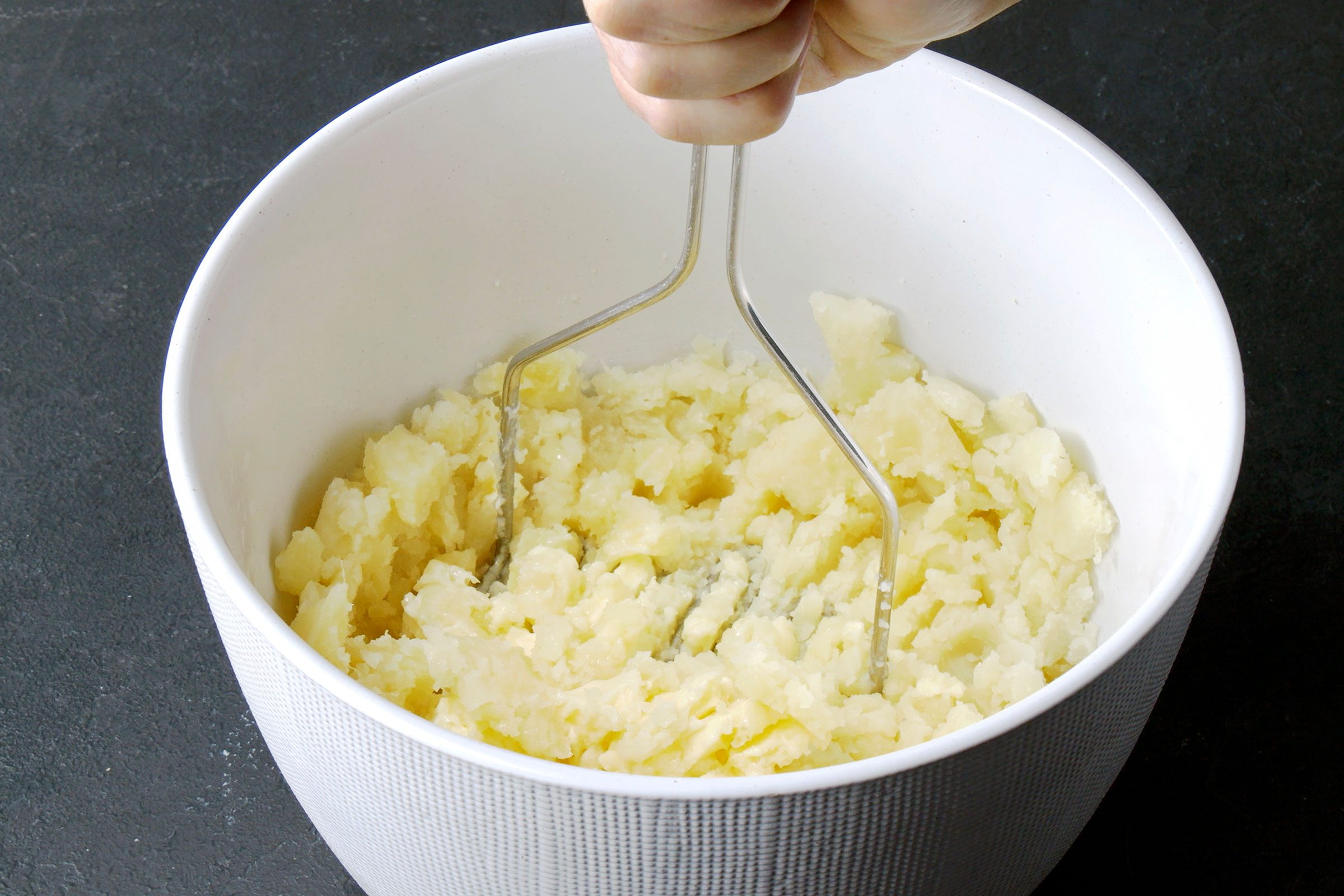 Mashing potato pulp in butter in a large bowl