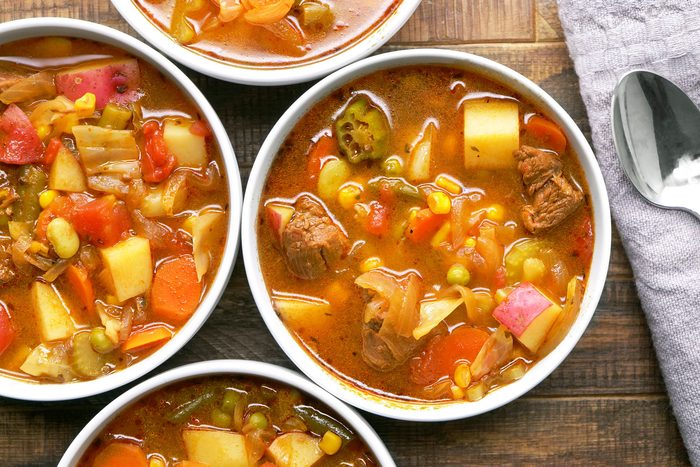 A hearty vegetable beef soup are arranged on a wooden table