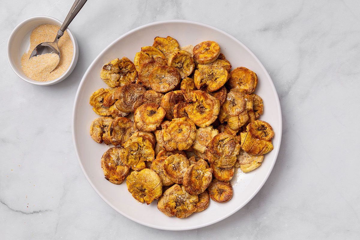 Garlic powder, garlic salt, onion powder and salt seasoning on crispy plantains for step five of Air-Fryer Plantains recipe for Taste of Home