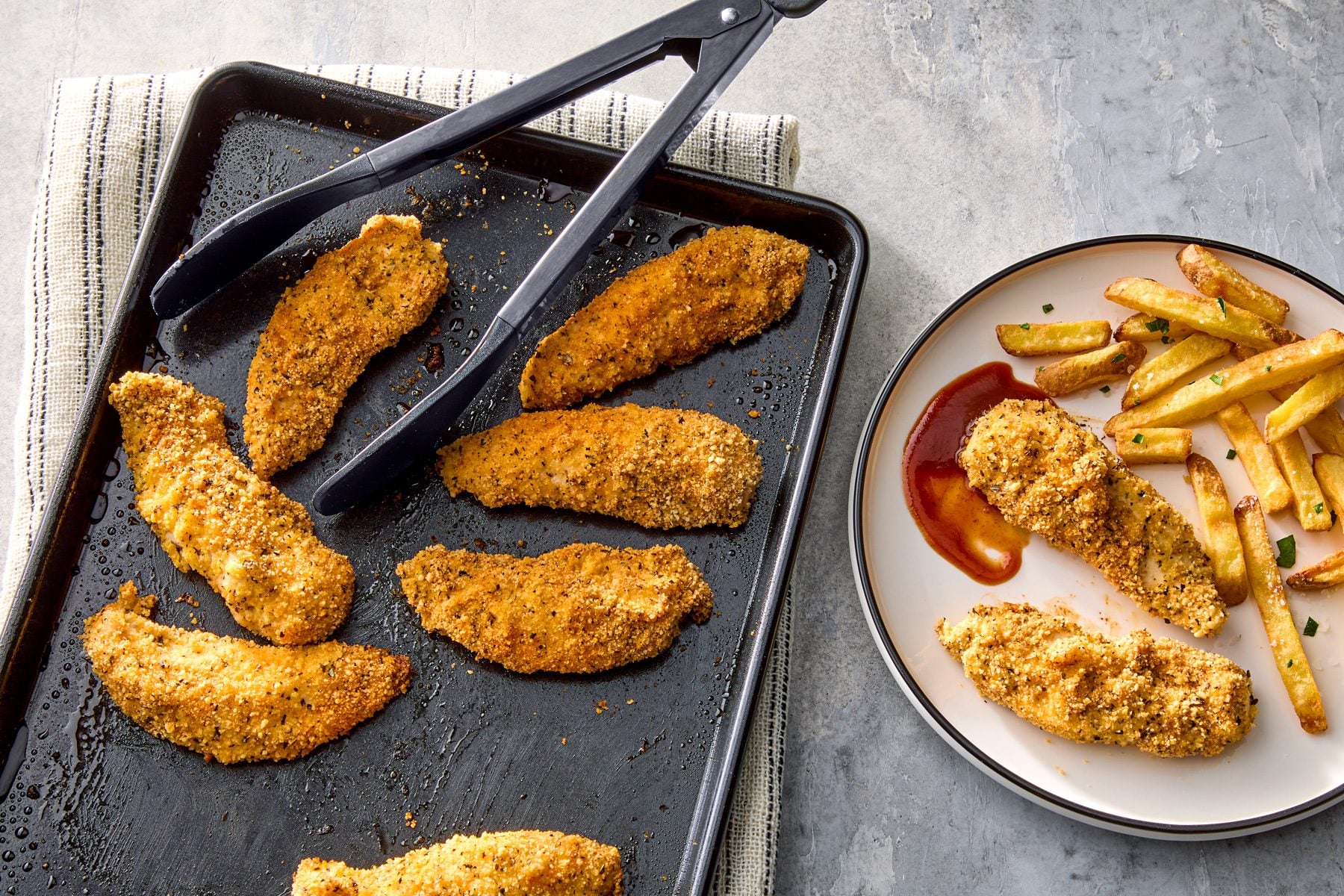 Seasoned chicken strips on a baking sheet.