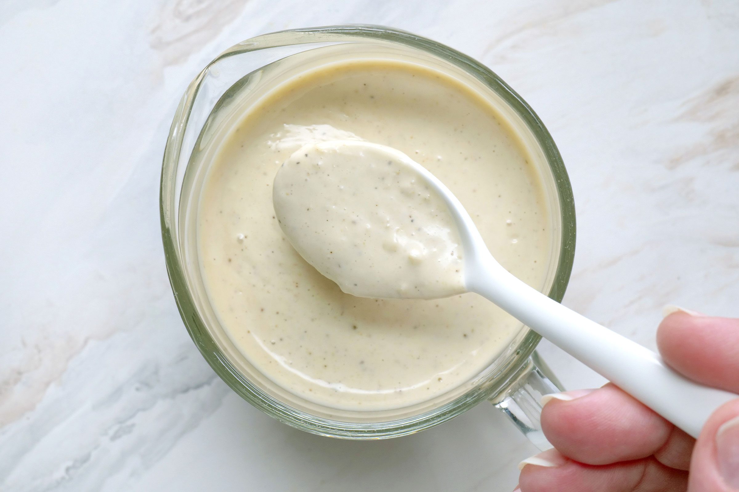 Caesar Dressing in a small glass jar with a spoon