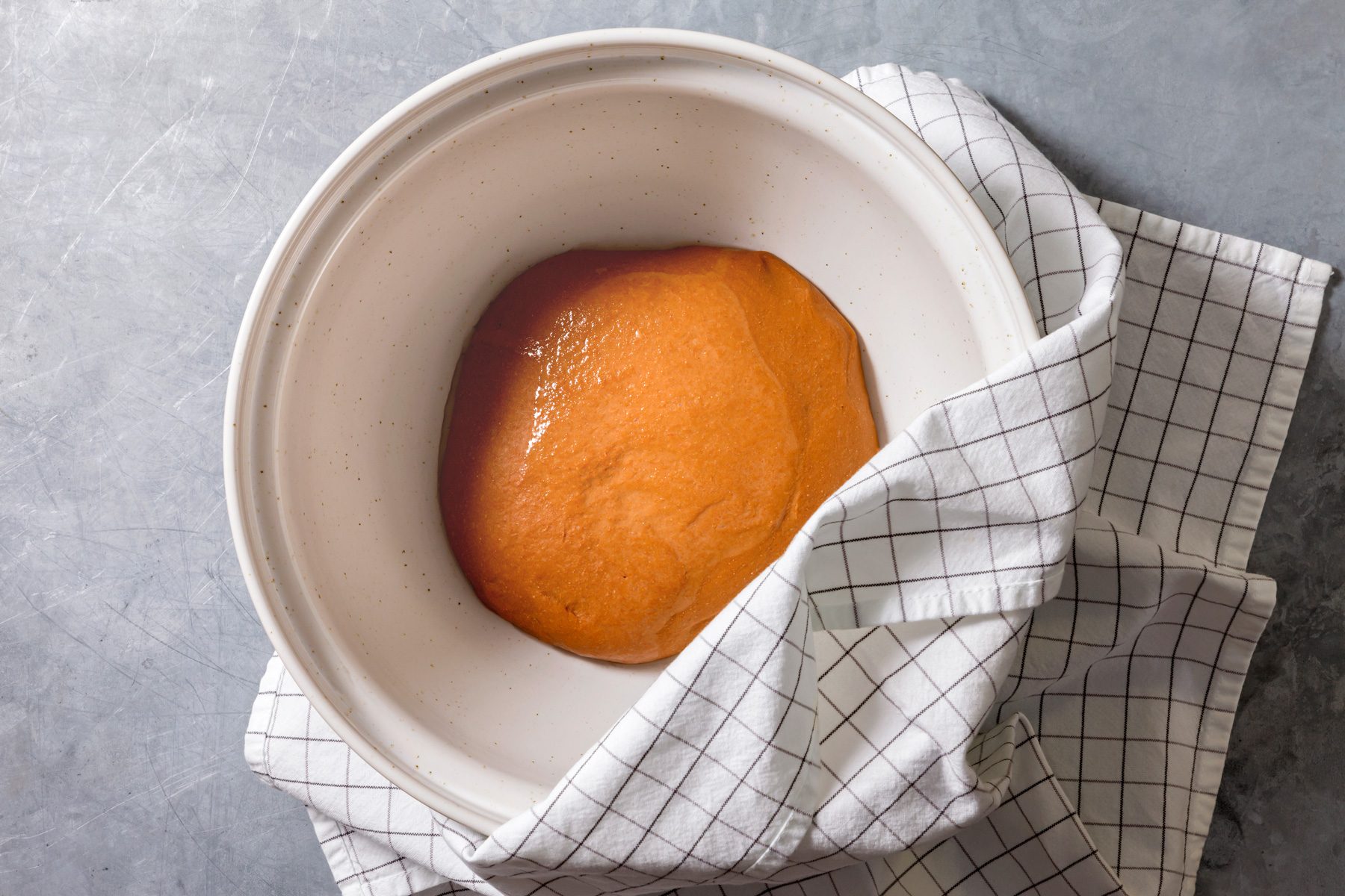 Overhead shot of transfer dough to a clean; lightly oiled bowl; cover; Let rise in a warm place until doubled in size; about 1-1/2 hours; kitchen cloth; grey surface;