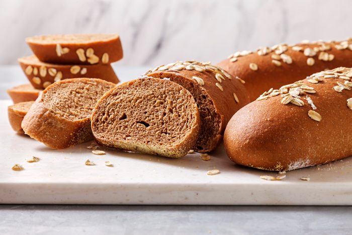 Table view shot of Copycat Cheesecake Factory Brown Bread; slice and serve warm with butter; knife; white board; grey surface;