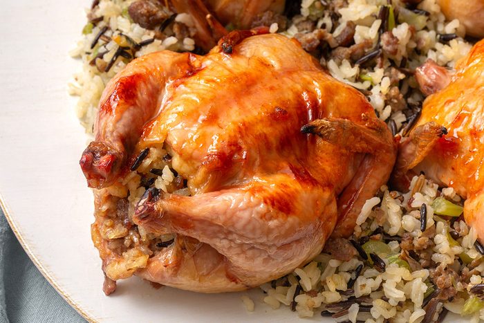 Close up of baked cornish game hens with wild rice stuffing on a serving plate for Taste of Home