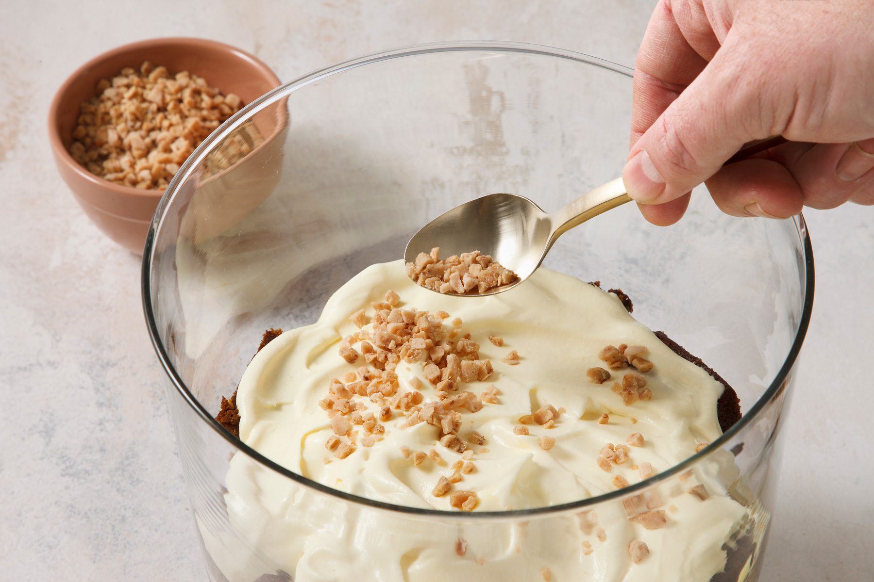 Close shot of top with remaining cake and pudding mixture; top with remaining whipped topping; sprinkle with remaining toffee bits; spoon; marble surface.