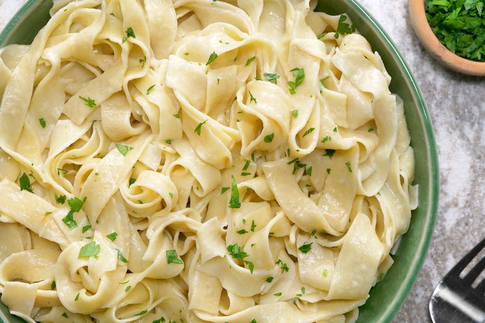 Egg Noodles sprinkled with parsley served in a green bowl