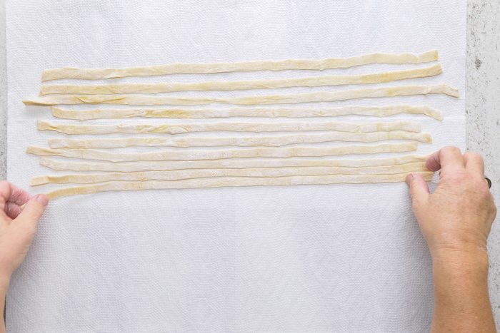 Unrolled noodles laying flat on paper towel