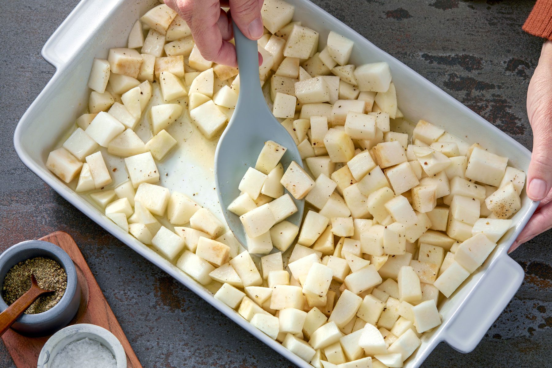turnips being tossed in a baking pan