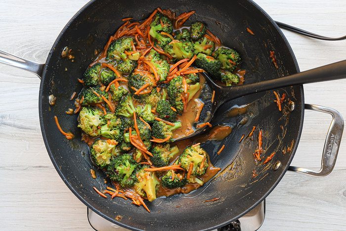 Stir-frying broccoli and carrots for a homemade peanut chicken stir-fry recipe.