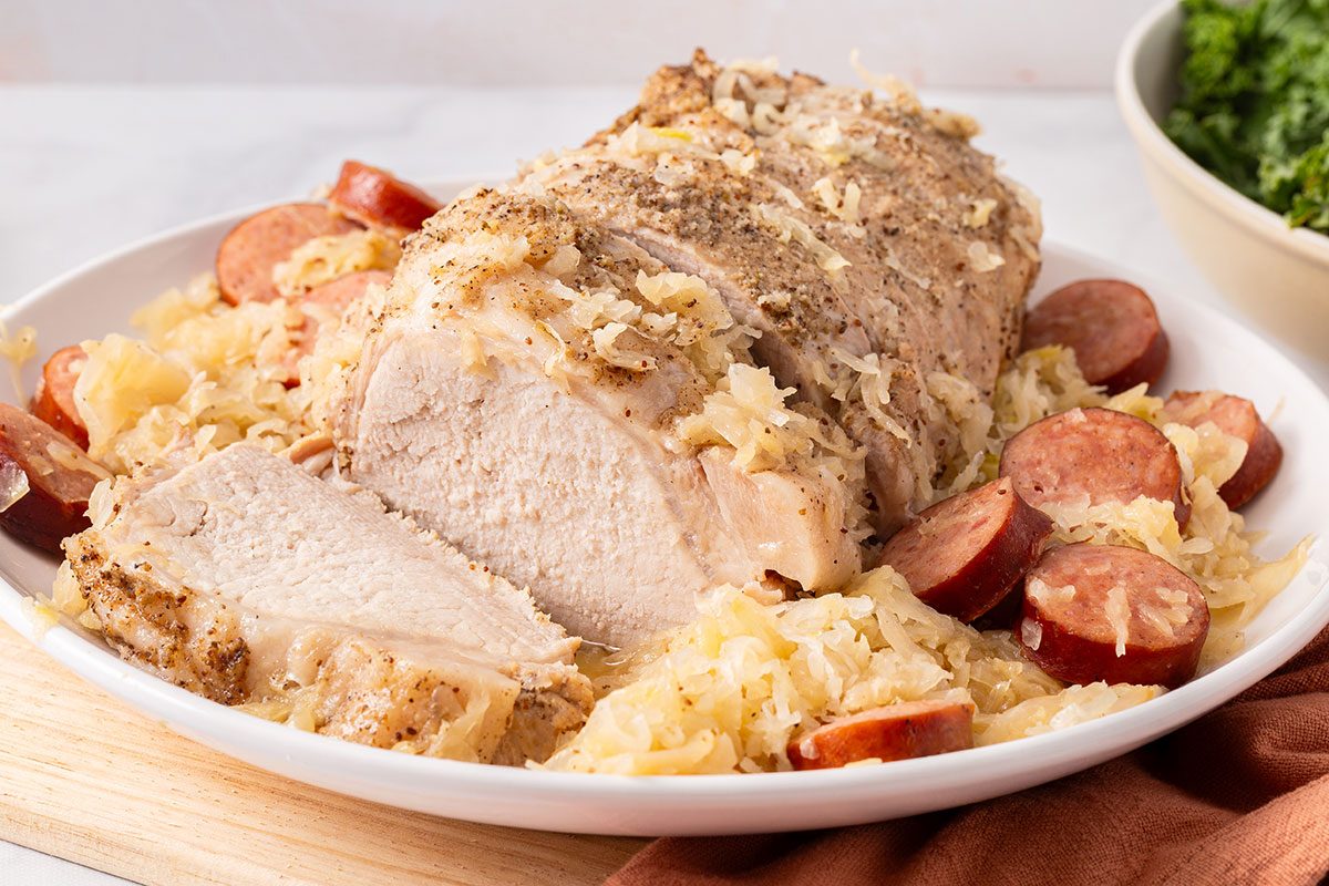 Pork Roast with sauerkraut and sliced polish sausage on a serving plate for Taste of Home
