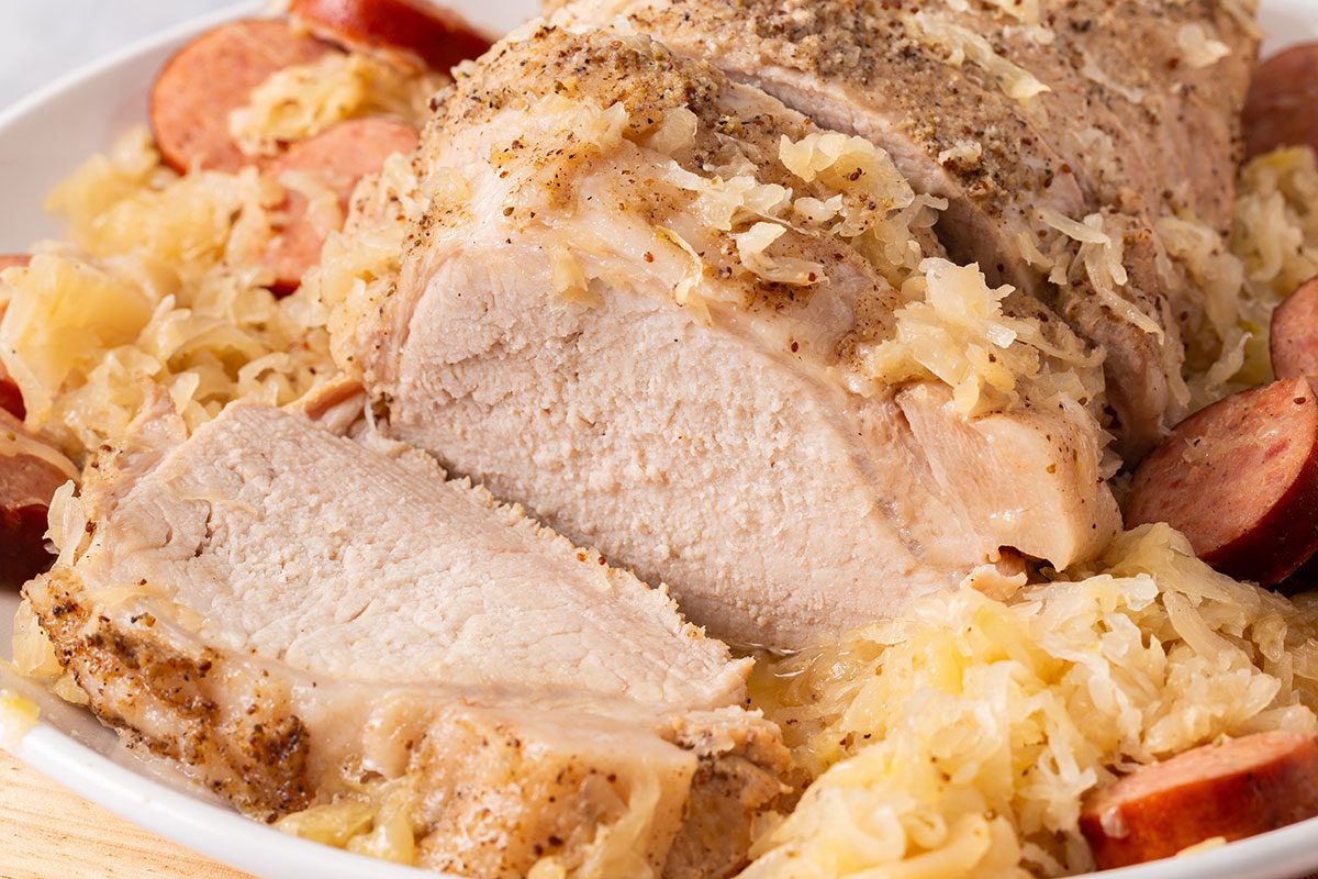 Close up of sliced pork roast with sauerkraut and sliced polish sausage for Taste of Home