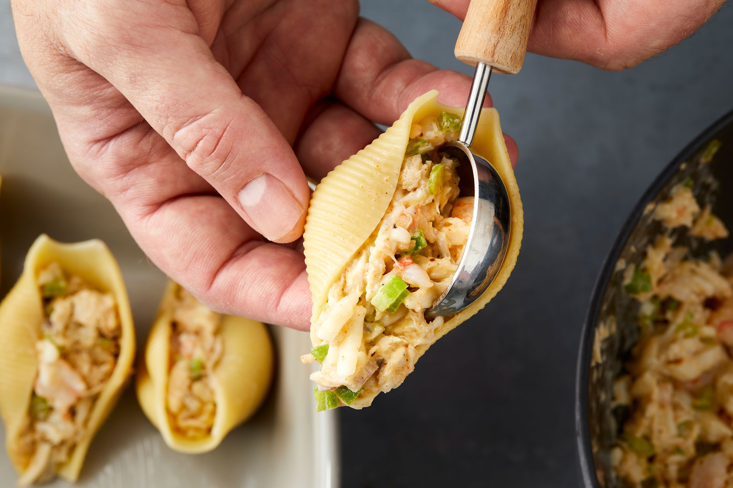 Seafood mixture being added to boiled pasta shells