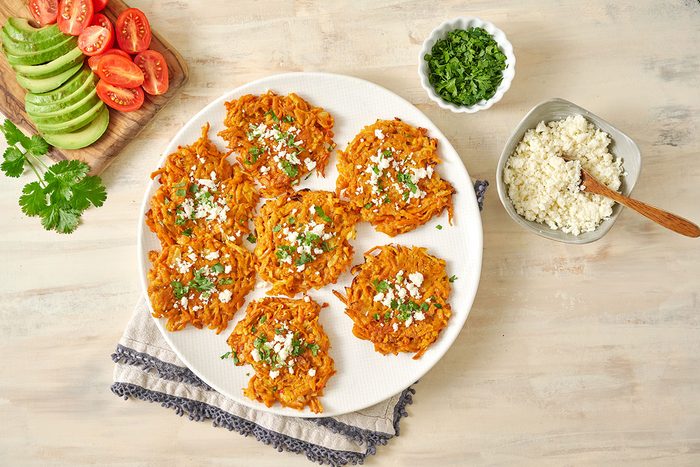 Overhead view of the fully cooked and golden brown Taste of Home Sweet Potato Fritters ready to serve with queso fresco.