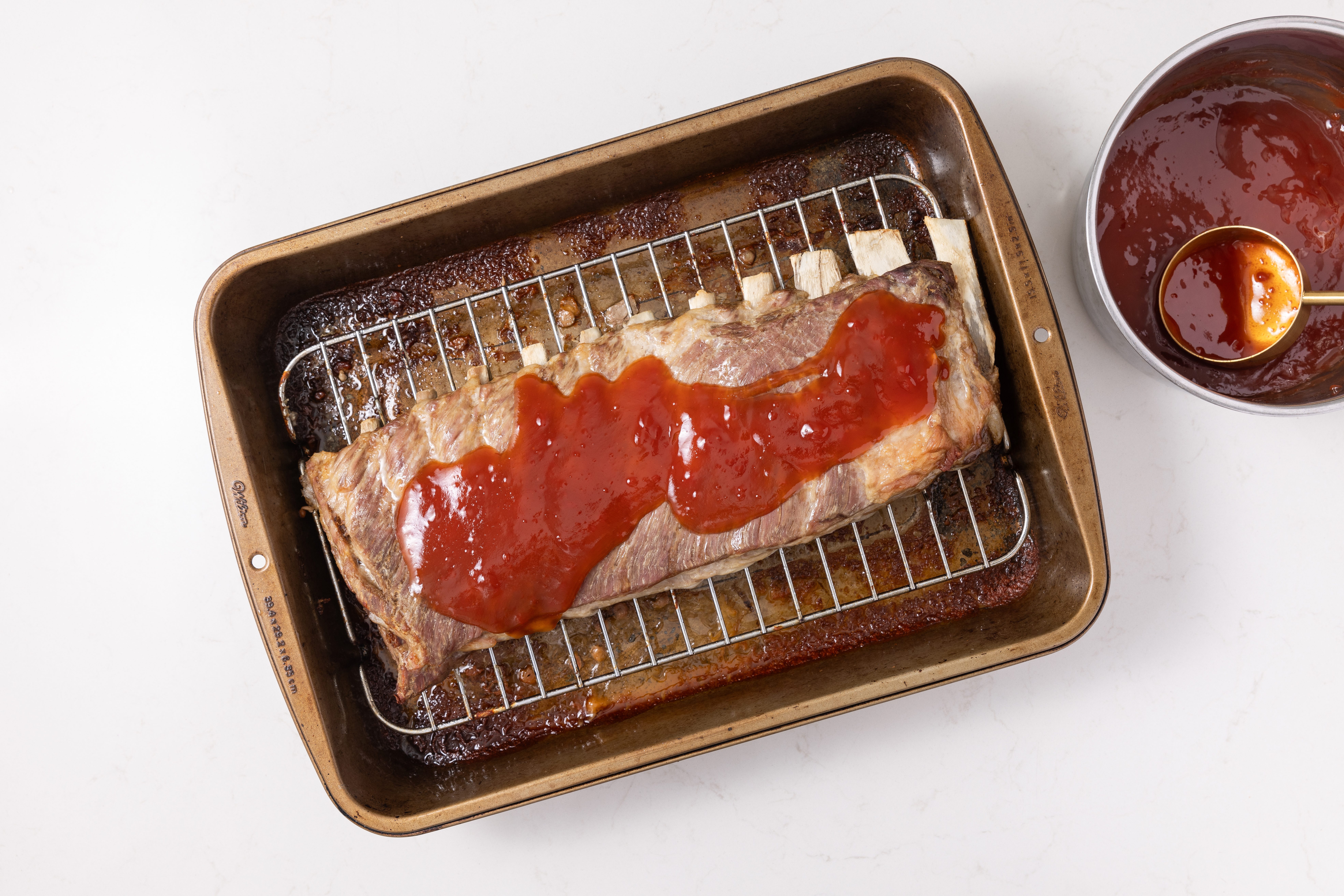 Spareribs baked and being glazed with sweet and sour sauce before returning to the oven.