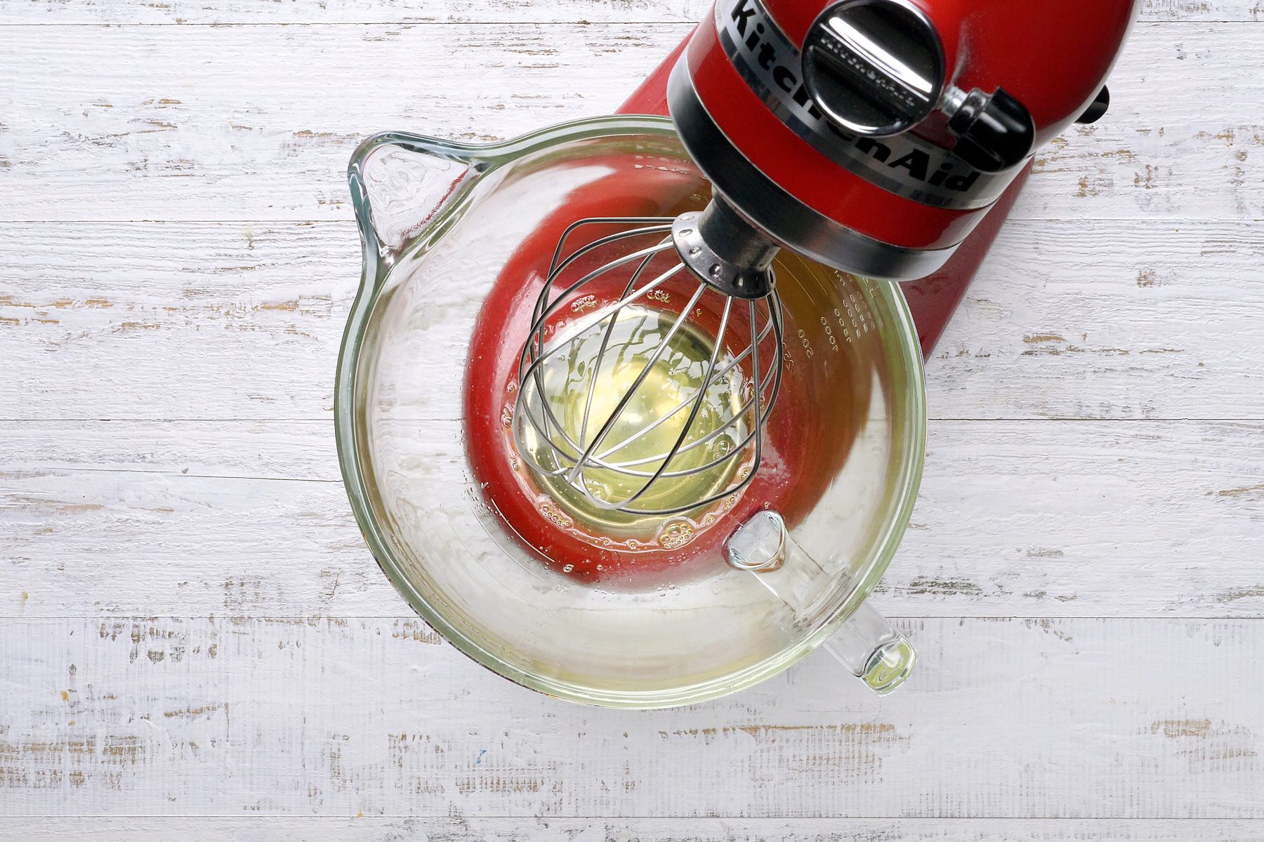 Egg yolks being beaten on high speed in a mixing bowl.
