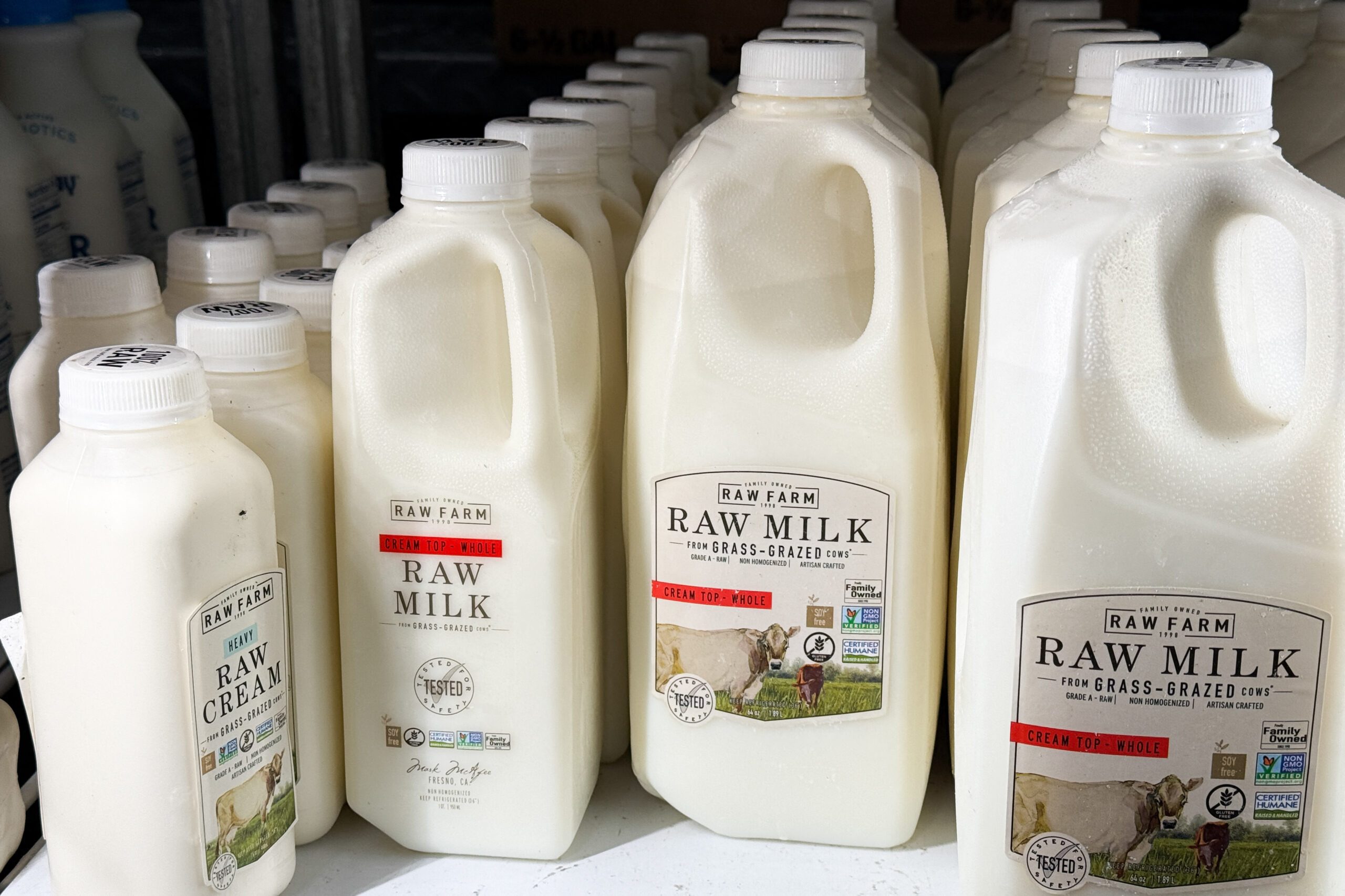 Several sizes of raw milk cartons on a shelf at a grocery store