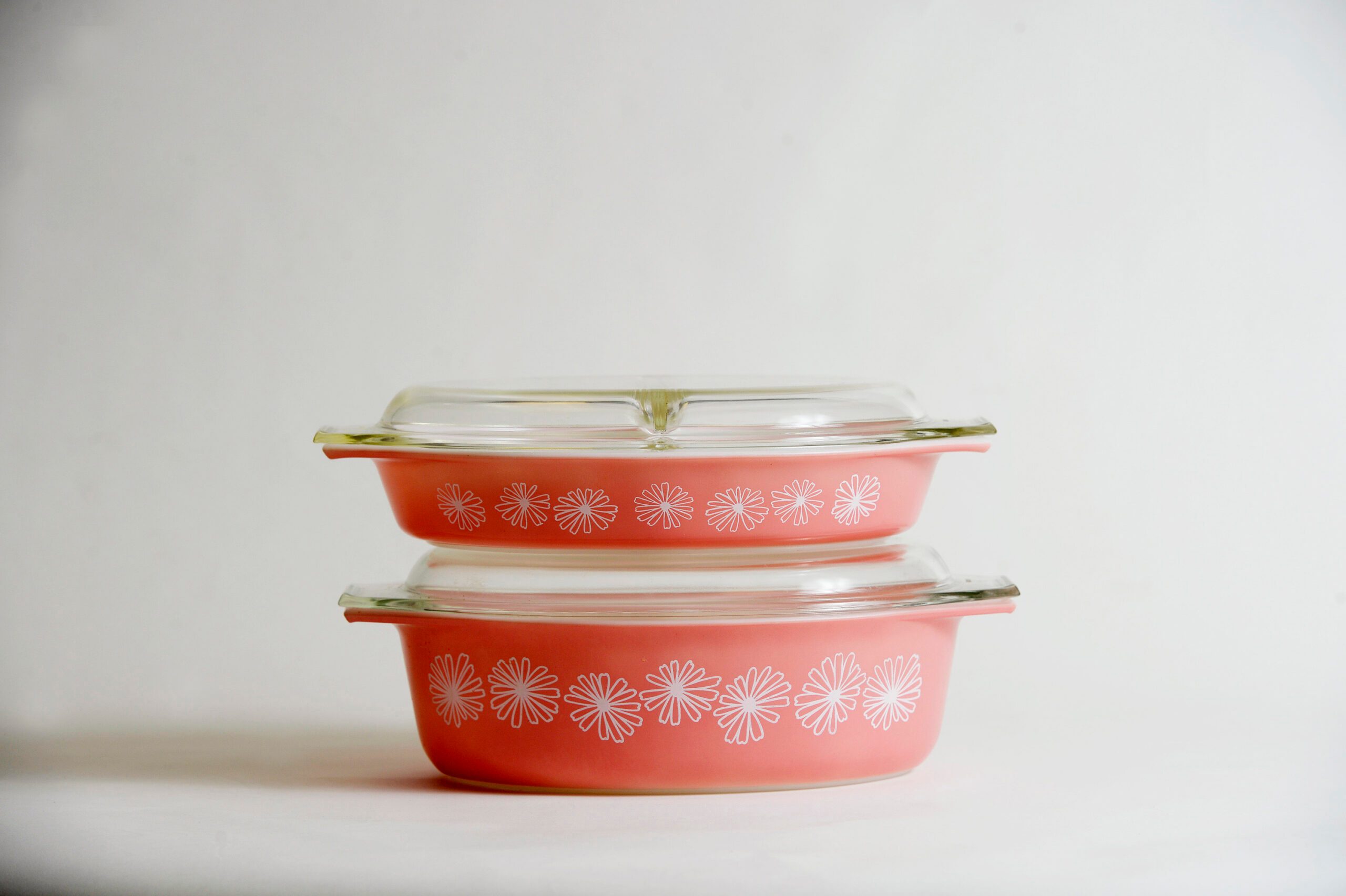 Two stacked vintage Pyrex bowls with the "pink daisy" design on a white background