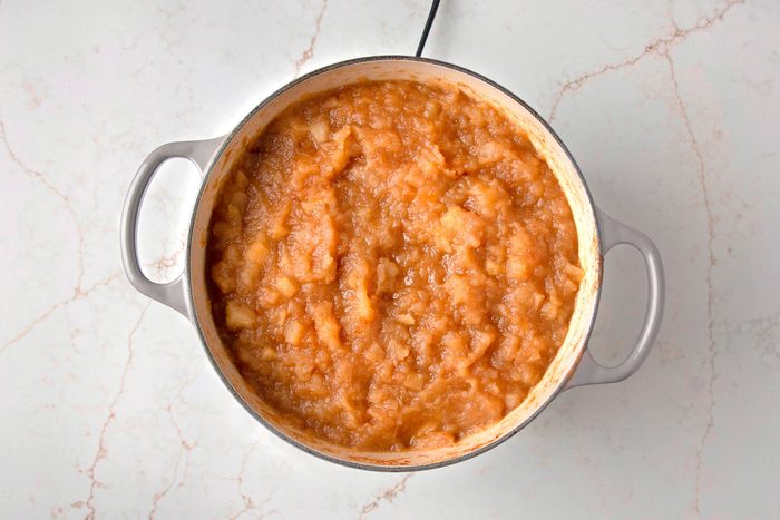 Overhead shot of a pot of applesauce sitting on a marble countertop