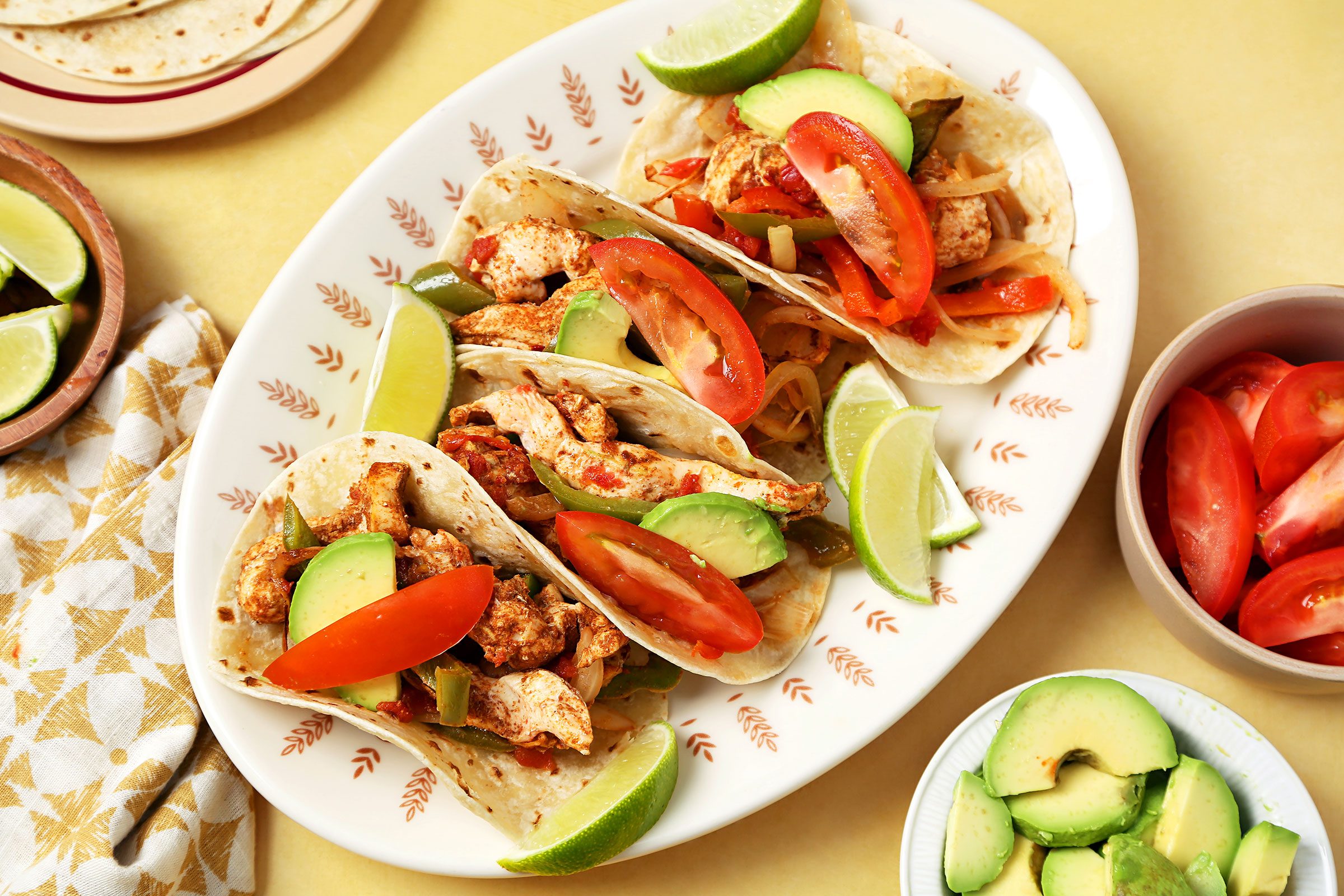 Baked Chicken Fajitas served in a plate with avocados and tomatoes on side