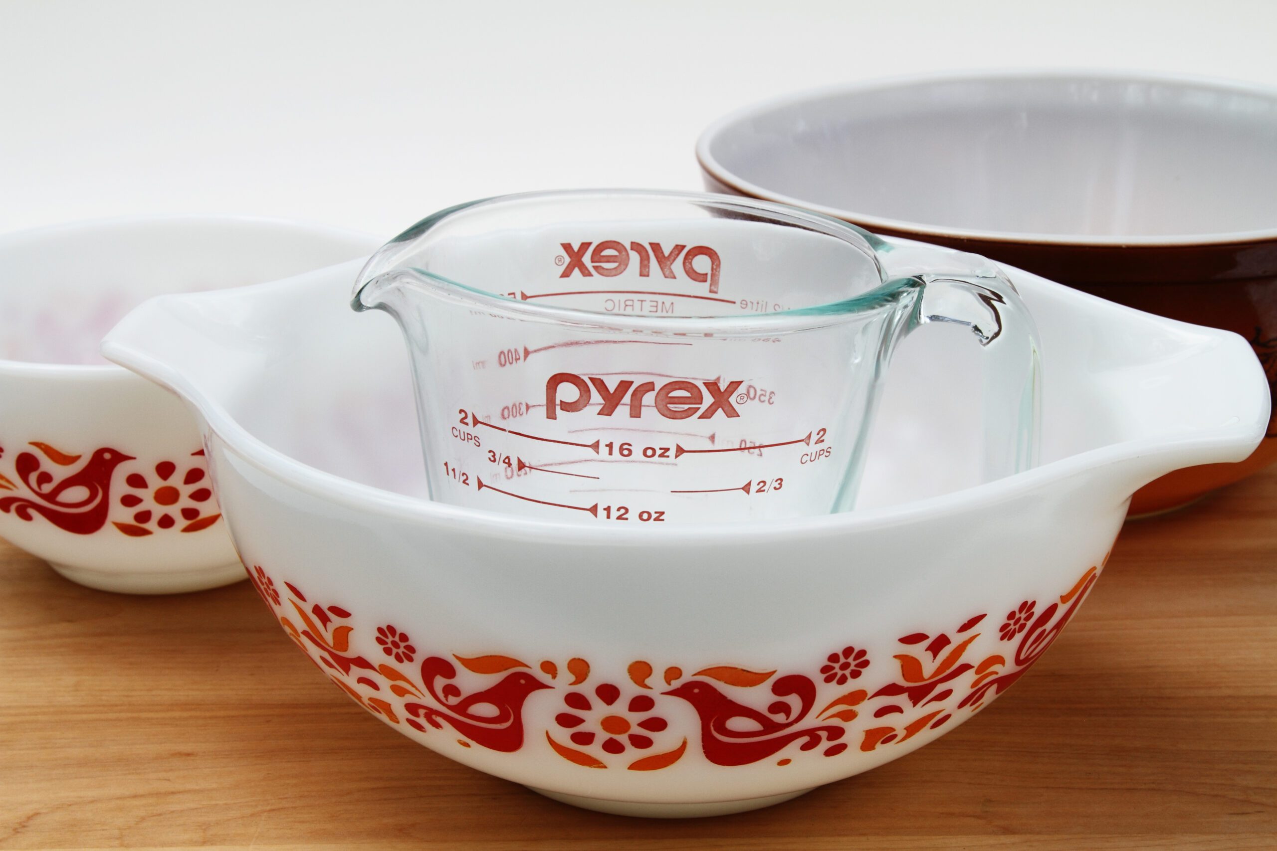 Pyrex measuring cup and mixing bowls on a wooden table