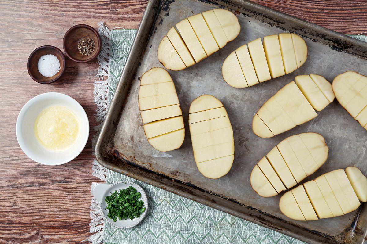potatoes cut lengthwise and sliced widthwise spread out on a tray