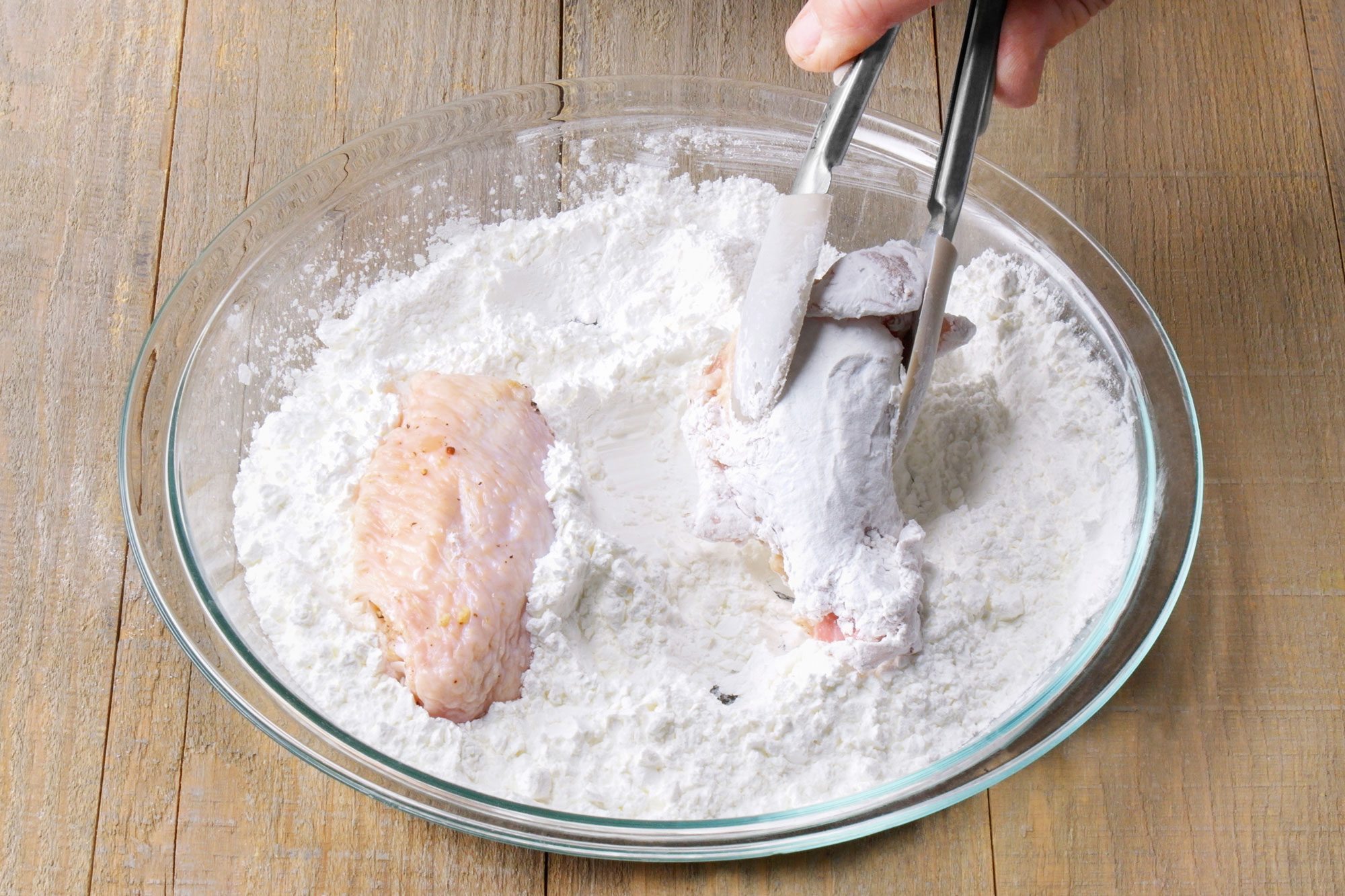 The chicken is being tossed in the flour