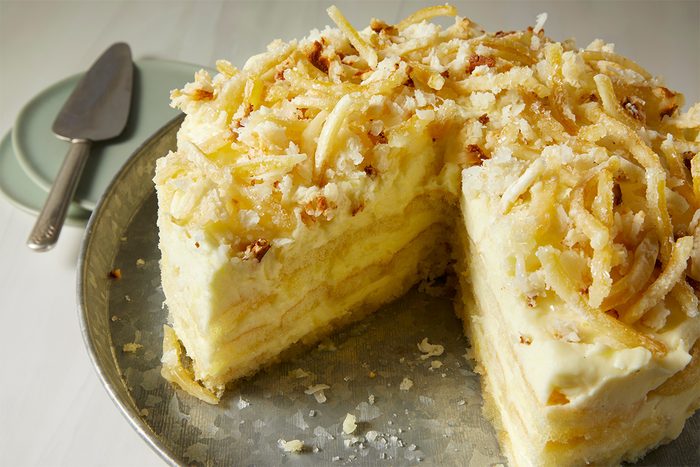 Limoncello tiramisu with a slice taken out of it on grey cake plate with serving spoon on the side horizontal.