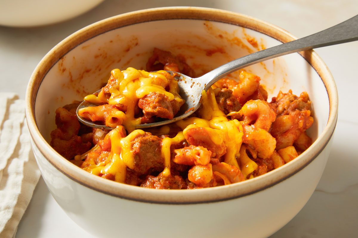 Close up shot of Turkey Taco Macaroni; serve in a bowl; spoon; napkin; marble surface