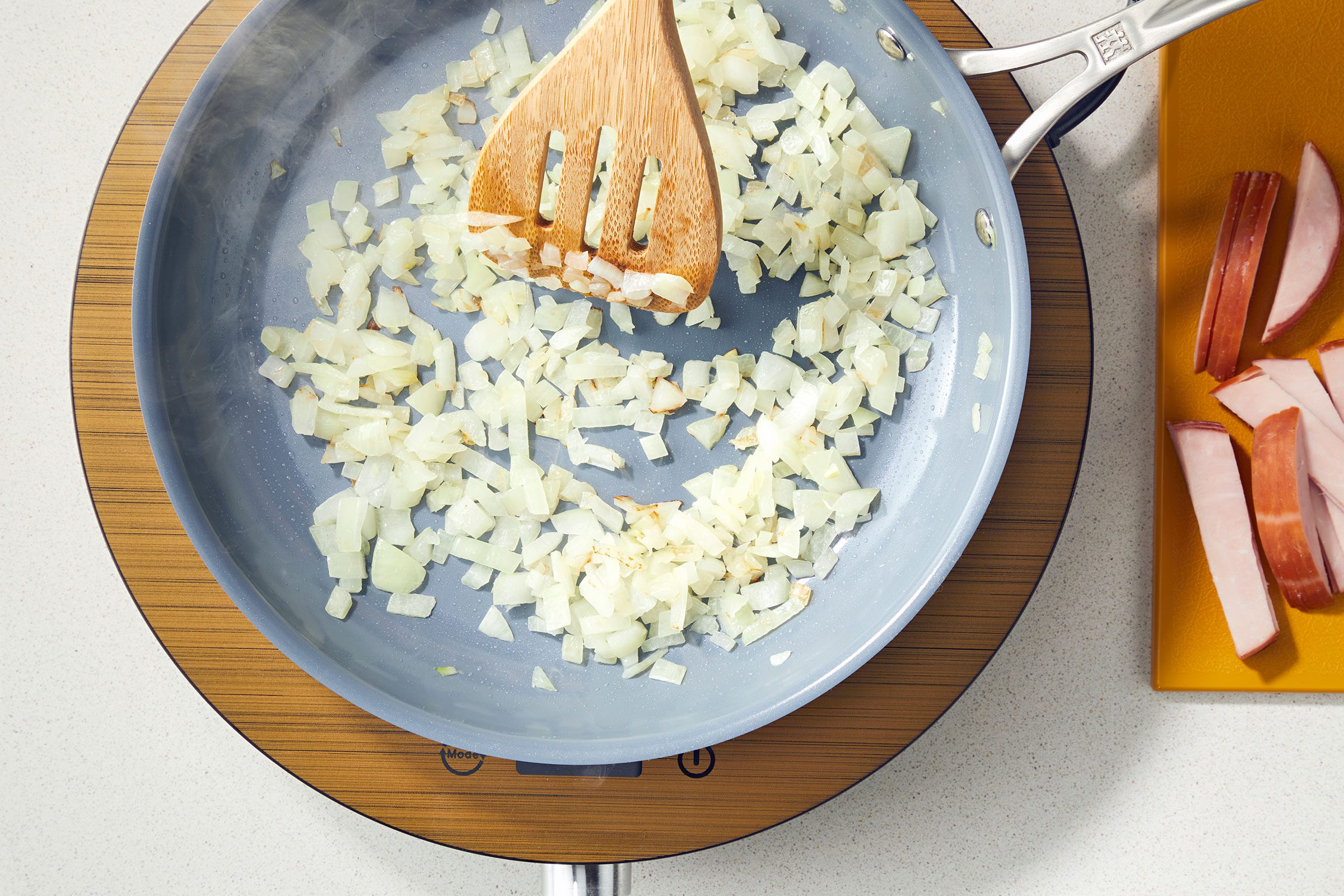 Cooking diced onions in oil in a large skillet and a ladle to stir them
