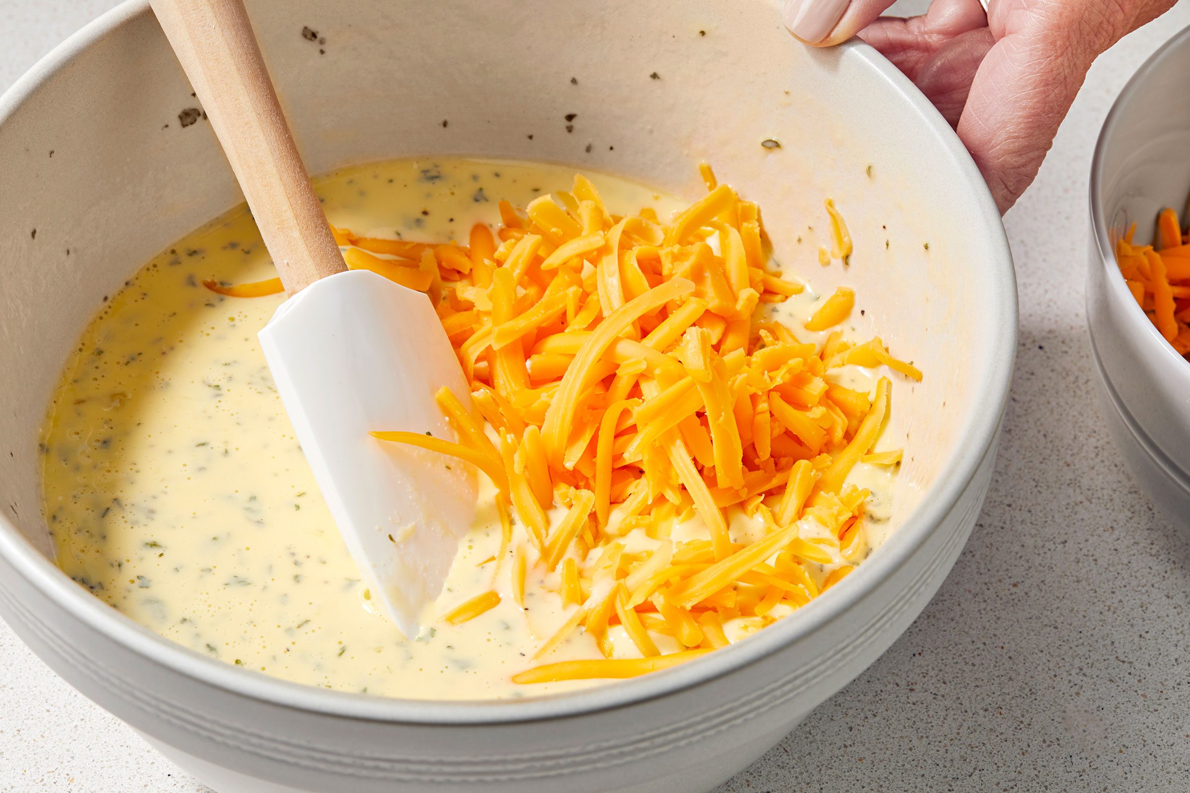 Grated cheddar cheese added to the eggs, cream and seasonings mixture