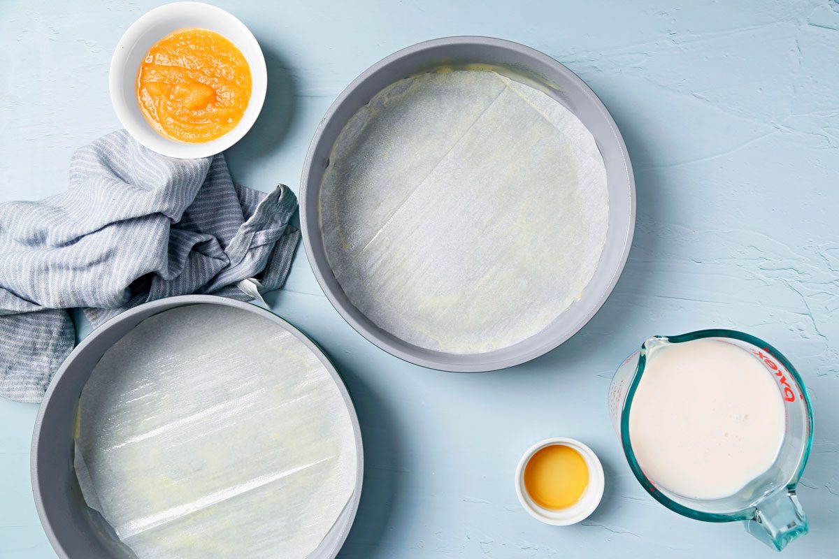 Vegan Chocolate Cake shot on a blue surface. Round cake pans greased and lined with parchment paper;