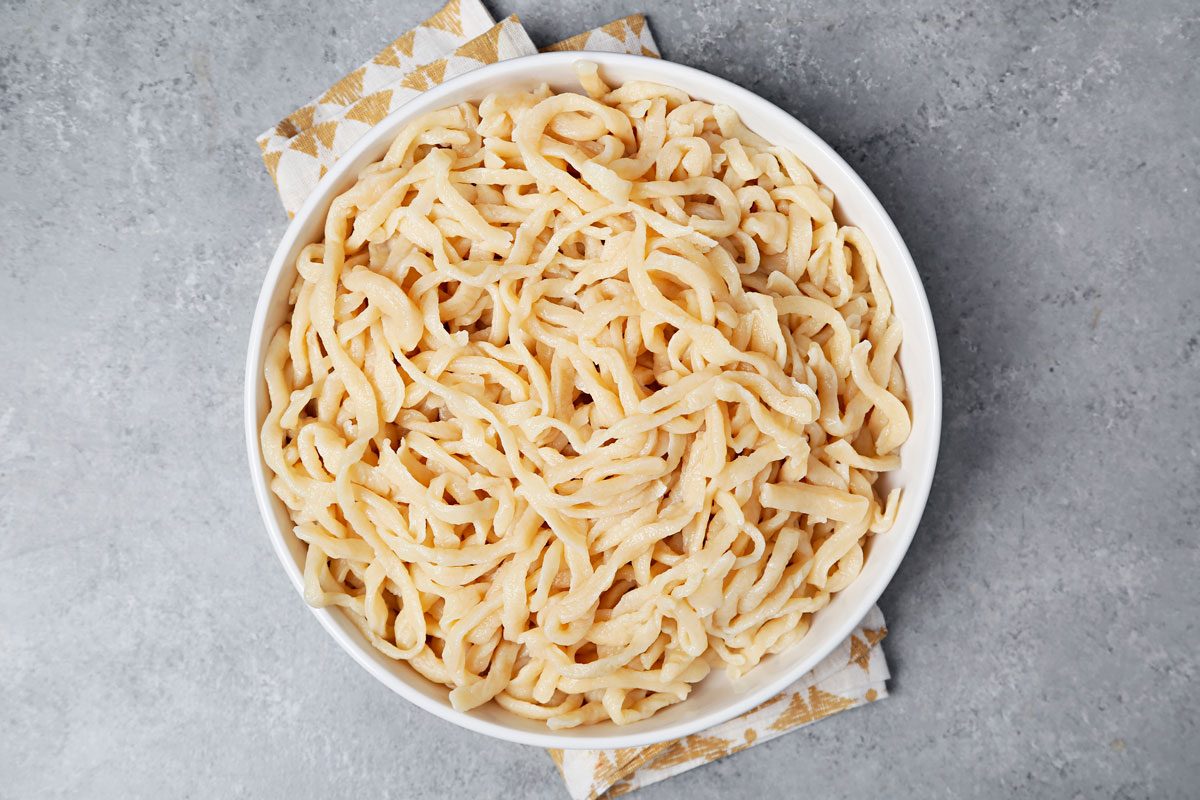 Boiled udon noodles in a large white serving bowl.