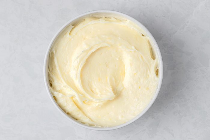 In a large bowl, beat cream cheese and butter kept on top of a grey marbletop.