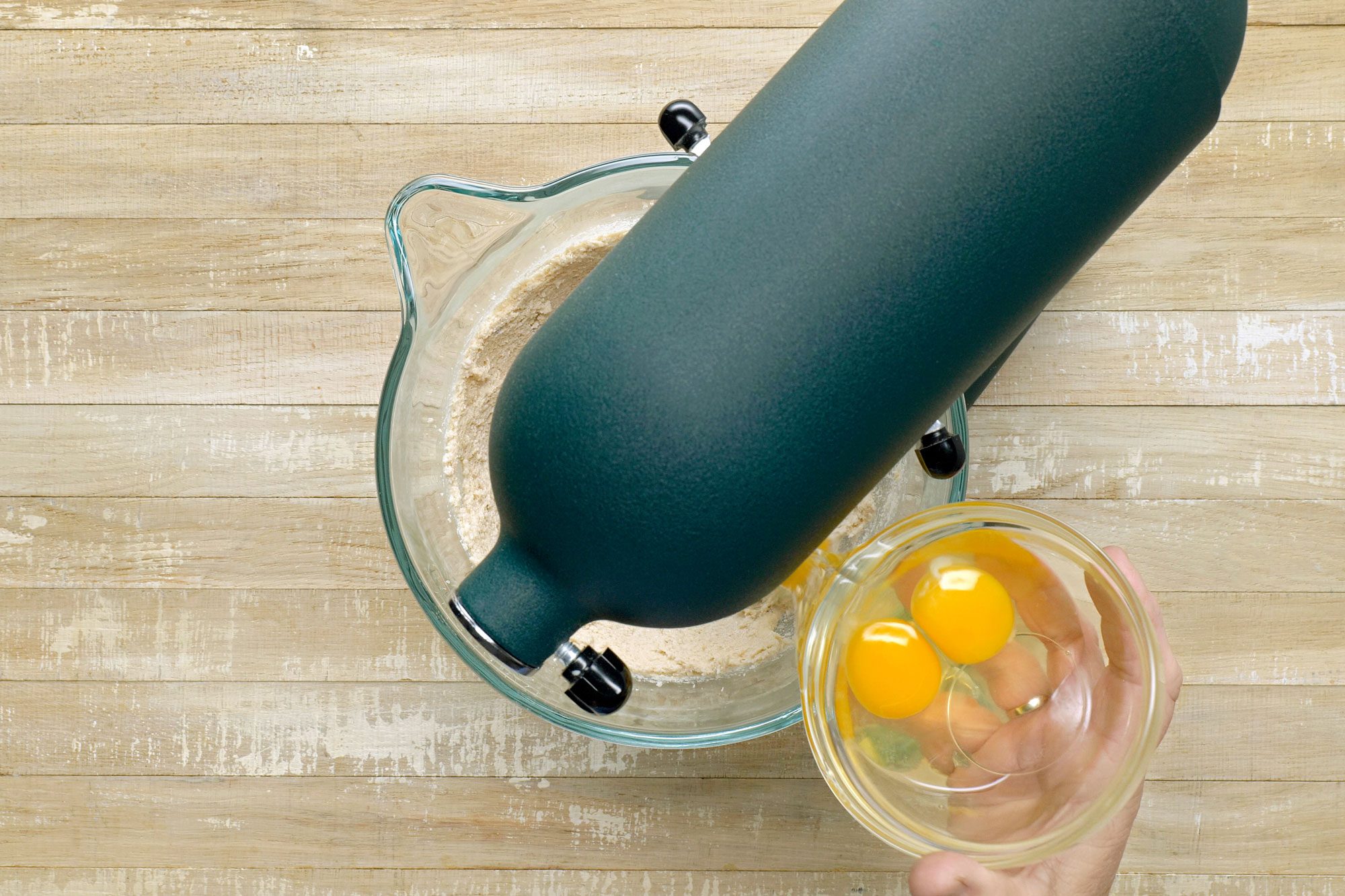 Overhead shot of Beat in eggs; one at a time; beating well after each addition; Beat in vanilla; wooden surface;
