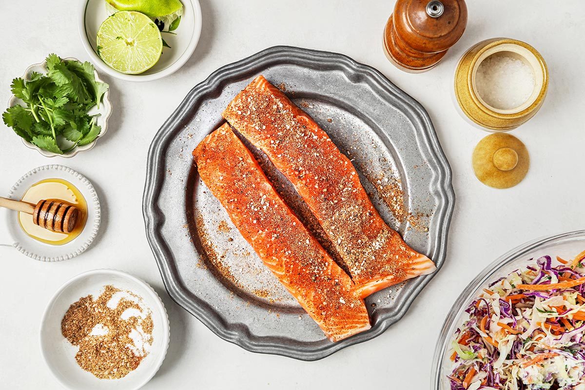 Salmon on a plate, seasoned with black pepper and salt.