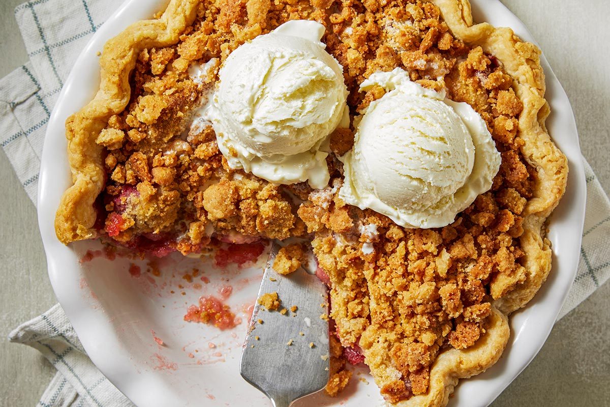 Strawberry crumble pie topped with two scoops of vanilla ice cream.