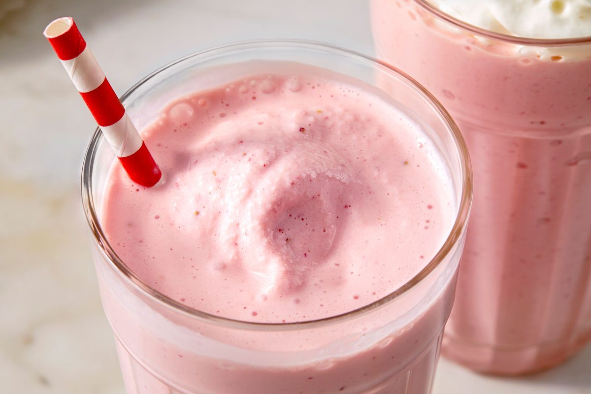 Close up shot of Springtime Strawberry Malts; serve in a glass; garnished with whipped cream; straw; marble surface;