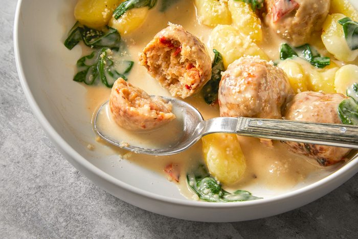 Tuscan Chicken Meatballs With Gnocchi in a big bowl with spoon in it