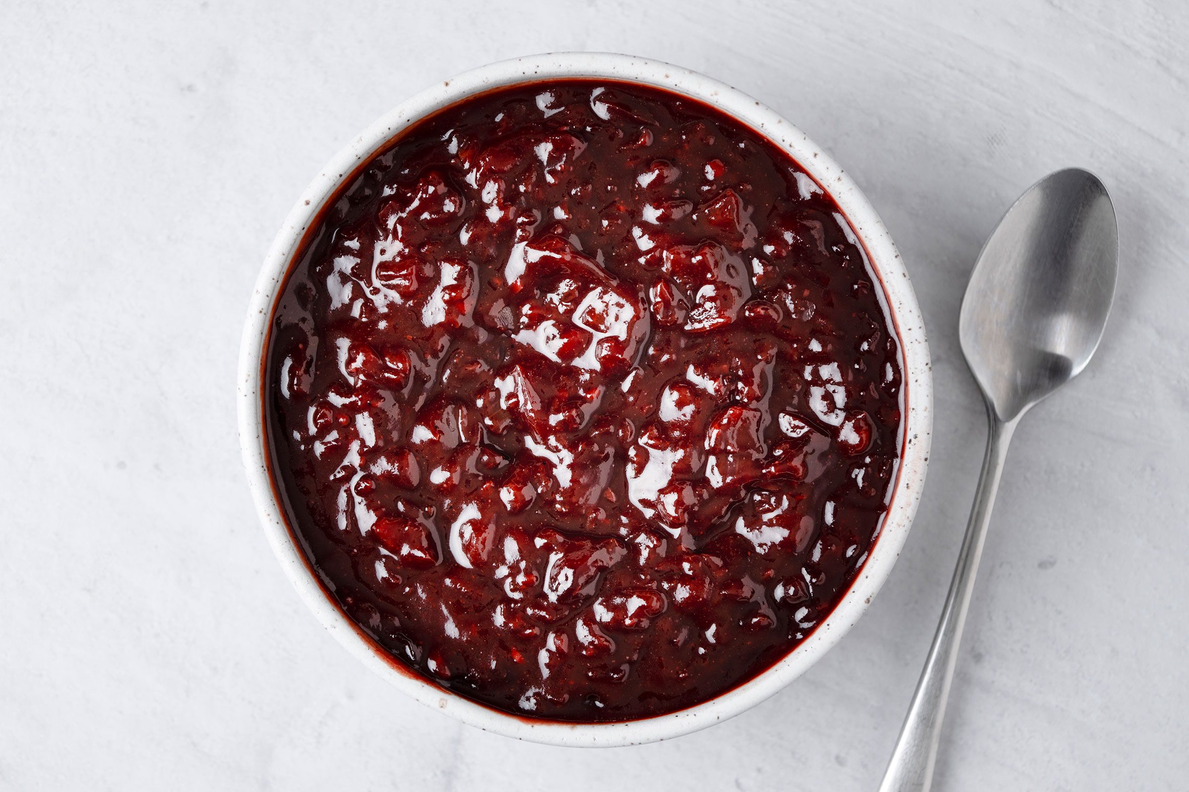 Cherry Barbecue Sauce in a white bowl with a metal spoon on side