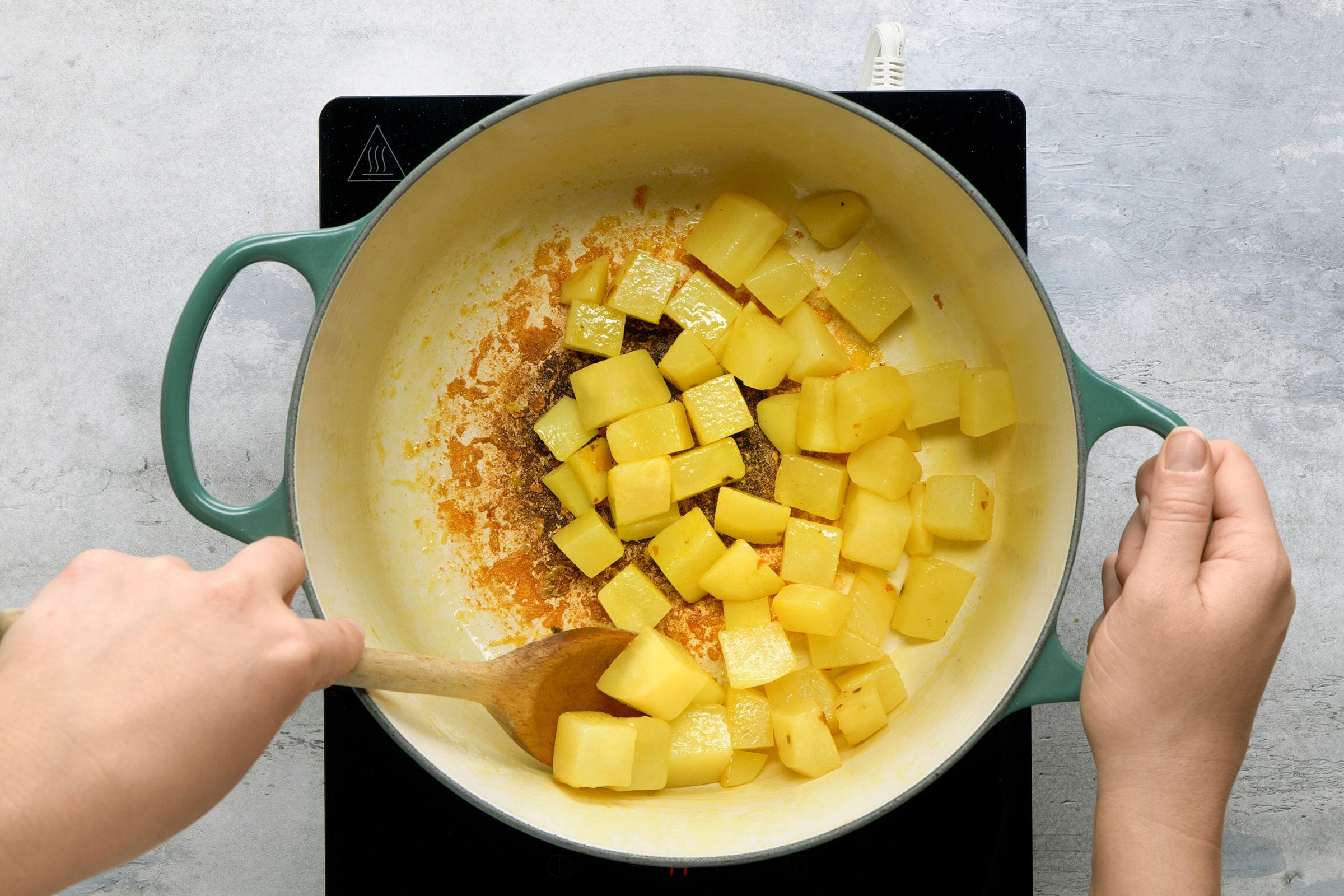 Cooking diced potatoes with ghee and turmeric in a dutch oven