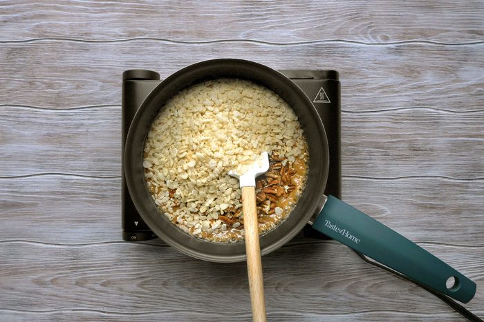 overhead shot of a pan of rice crispy treats on a stovetop, a white spatula resting on top of the treats; the pan is on a black electric stovetop that has a green handle