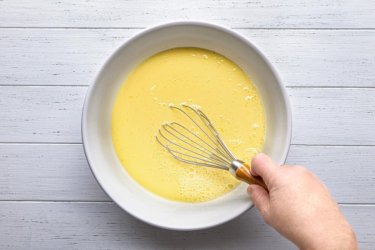 Egg and milk being mixed in a large bowl